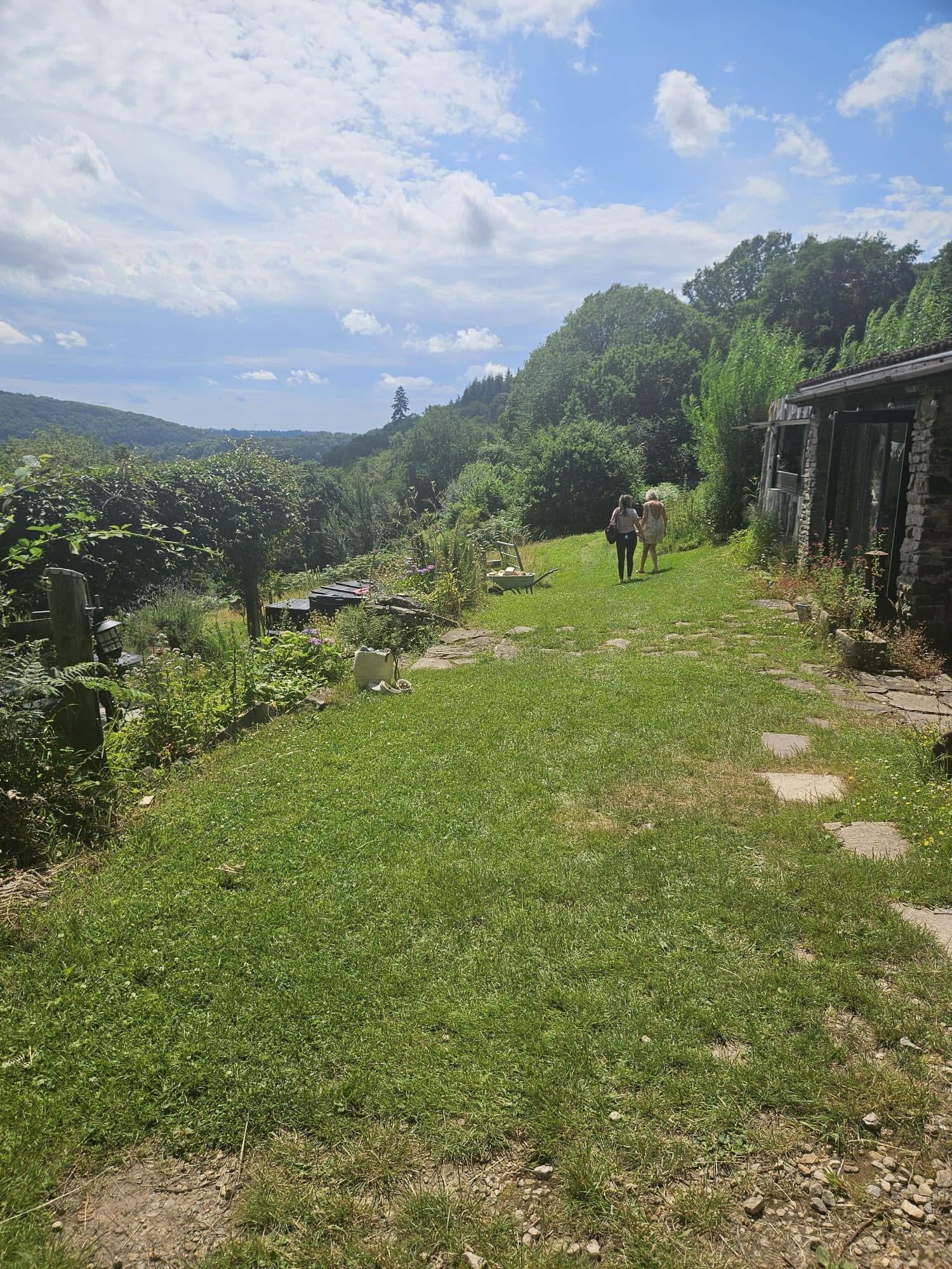 A garden path leading towards a stone barn and valley